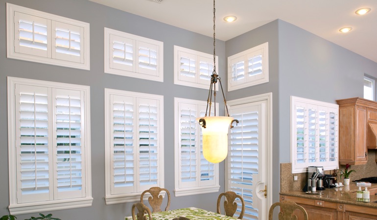 Plantation shutters can fix both sun glare and energy efficiency problems. White plantation shutters in kitchen
